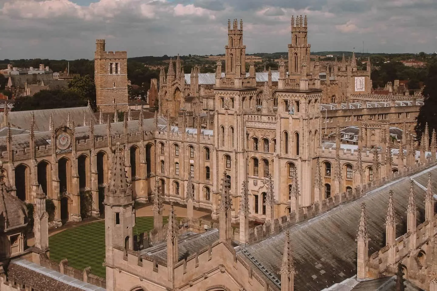 Historic college rooftops and towers beneath a blue sky