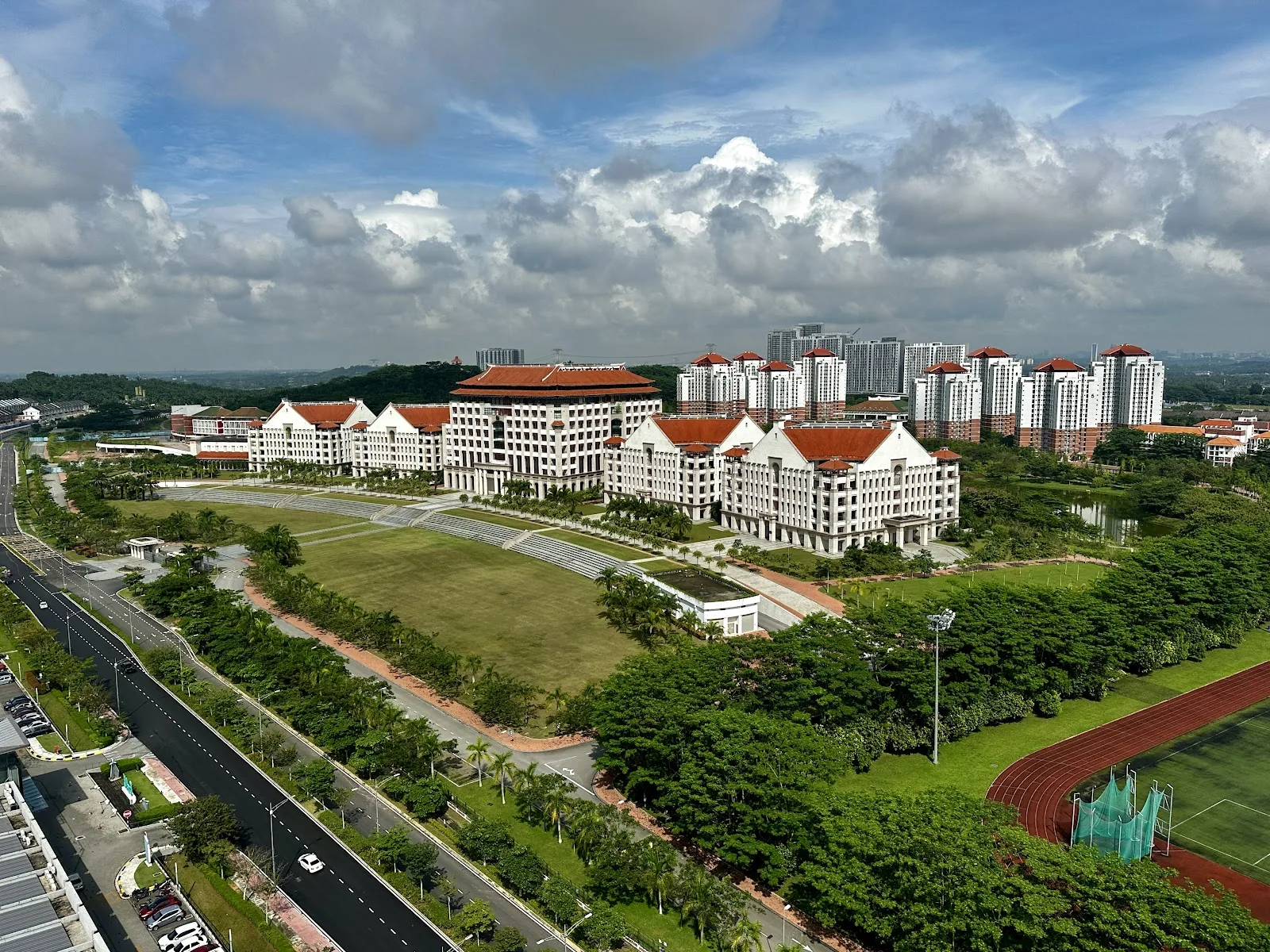 White campus buildings and sports grounds beneath a cloudy sky